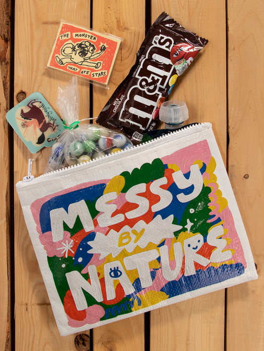 A white zipper pouch with green, blue, pink, red and yellow paint splats on the front. The text reads: Messy by nature