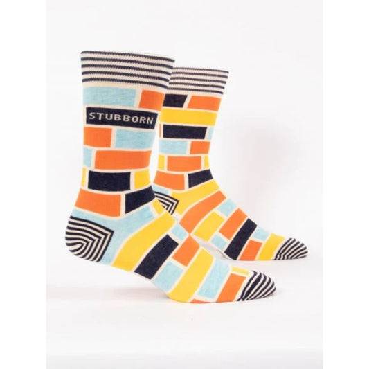 Blue Q socks with a orange, blue and yellow brick like pattern on them. The text on the socks reads ‘stubborn’