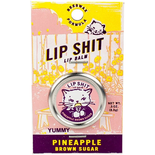 A Blue Q lip shit tin encased in a pink cardboard packaging. The text reads: 'Lip shit lip balm Pineapple brown sugar'