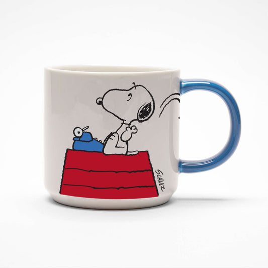 A white mug with a blue handle. There is a graphic of Snoopy on a typewriter throwing some paper over his shoulder.