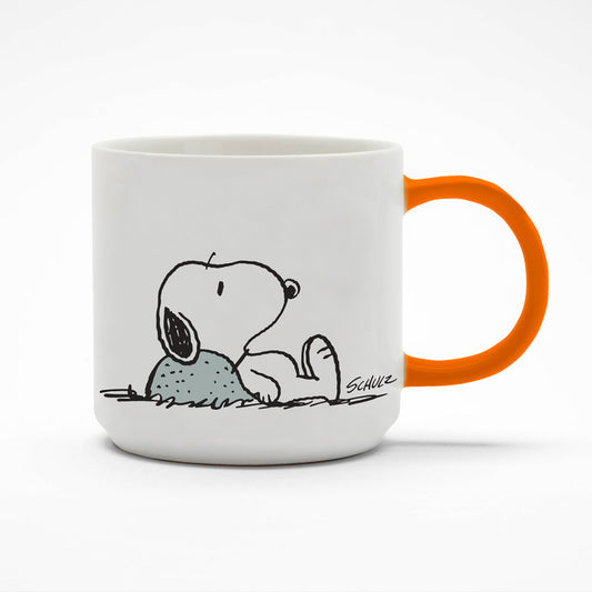 A white mug with an orange handle. On the mug is a graphic of Snoopy laying down with his head on a rock looking a little deflated. 