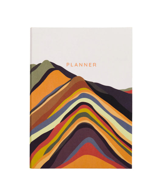 A white notebook with yellow, orange, red, brown, blue and green mountains on the front. The text on the book reads: planner