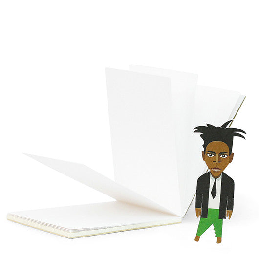 A paper cut out book mark of Basquiat stood in front of a sketch pad 